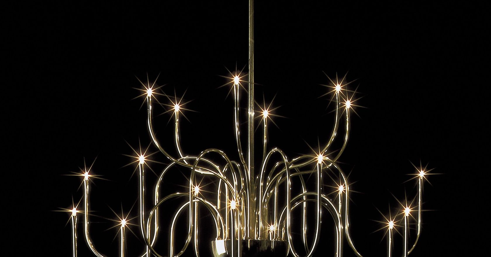 A multi-arm Florian Schulz brass chandelier lit against a dark interior, no people
