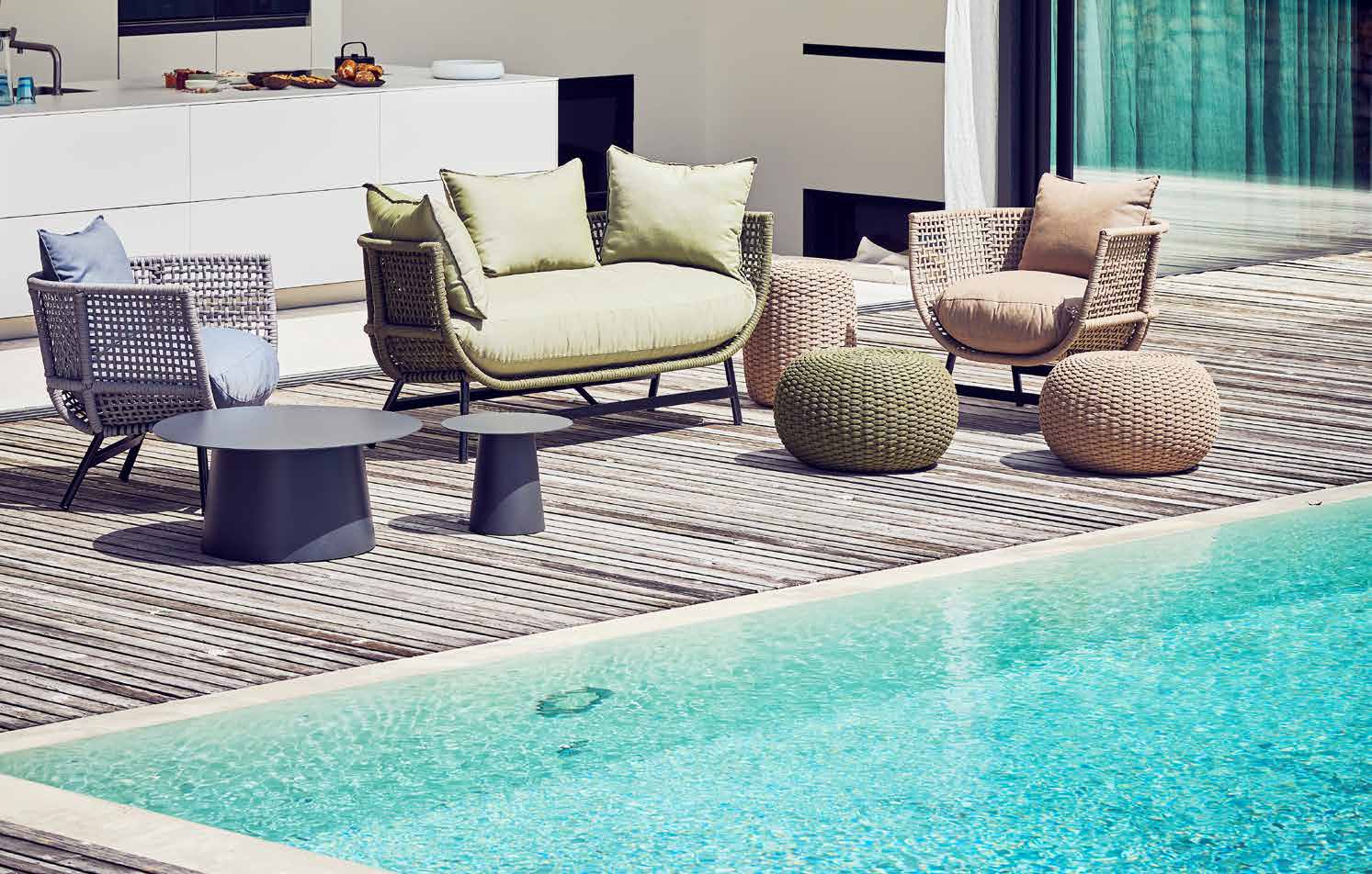 A Jan Kurtz outdoor lounge setting in woven fibre and teak on a timber poolside deck, no people