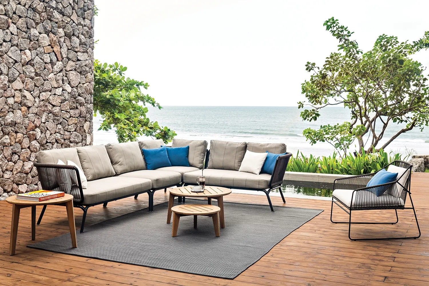 An Oasiq Yland modular sofa set with rope-detailed frames on a timber deck beside the sea, no people